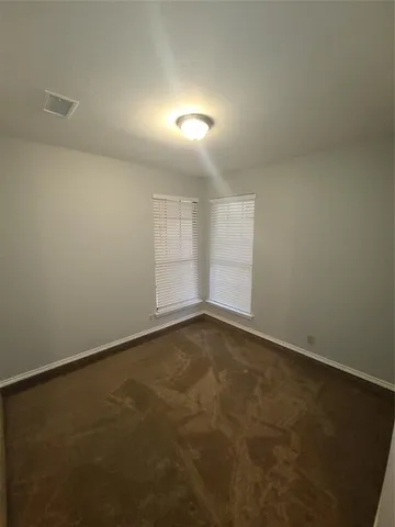 an empty room with a chandelier fan and windows