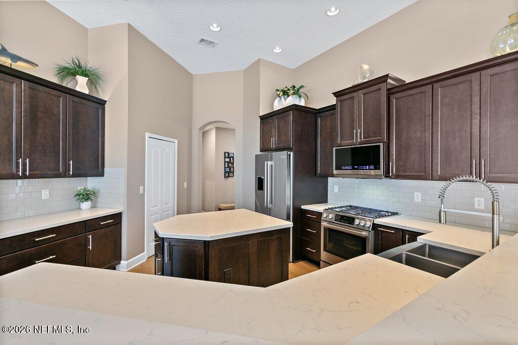 841 Ifield Road St. Augustine, FL 32095 - Photo 16 of 69 a kitchen with stainless steel appliances a sink a stove a refrigerator cabinets and chairs