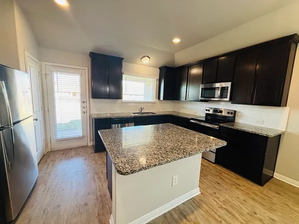 a kitchen with stainless steel appliances granite countertop a stove a sink and a refrigerator