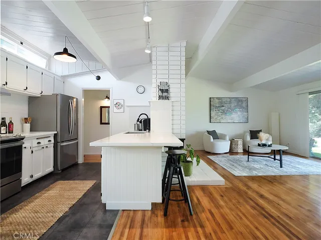 a kitchen with a sink appliances and wooden floor