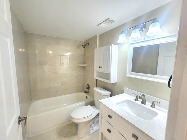 a bathroom with a toilet a sink a mirror a bathtub and shower