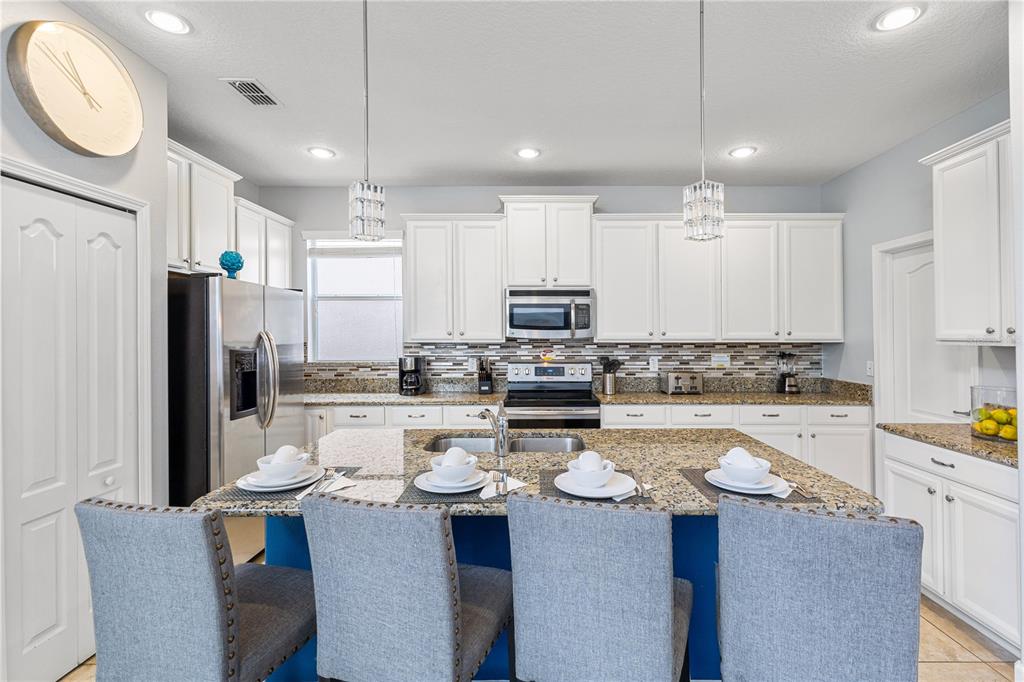 9006 Majesty Palm Road Kissimmee, FL 34747 - Photo 17 of 56 a kitchen with a sink a stove a refrigerator and white cabinets with wooden floor
