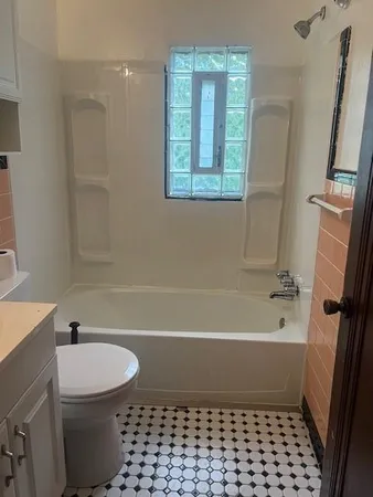 a view of a hallway with wooden floor and a bathroom