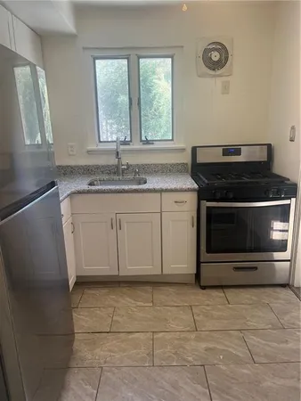 a kitchen with granite countertop a stove top oven cabinetry a sink and a window