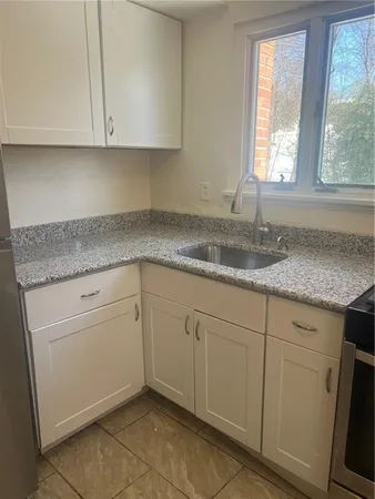 a kitchen with granite countertop white cabinets and a sink