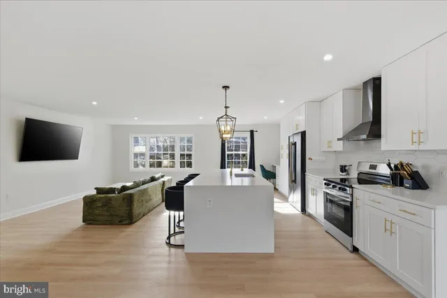 a living room with stainless steel appliances furniture a flat screen tv and kitchen view