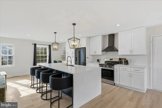 a kitchen with stainless steel appliances granite countertop a stove a sink dishwasher a microwave oven and a dining table with wooden floor