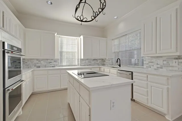 a kitchen with white cabinets appliances a sink and a window
