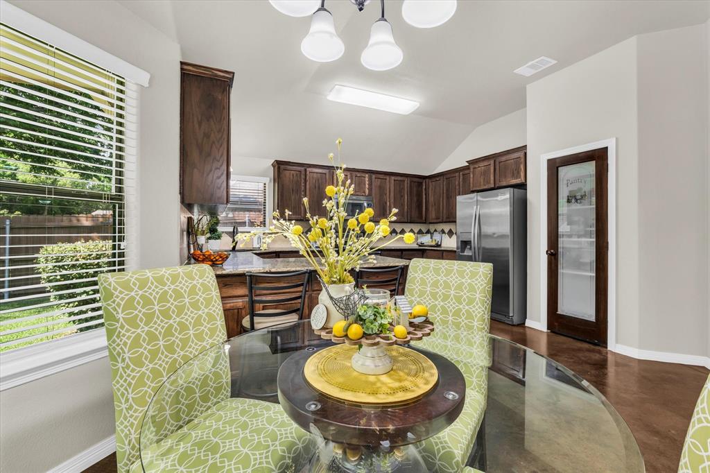 814 Springdale Circle Lorena, TX 76655 - Photo 11 of 37 Open-concept dining area featuring a glass-top table, wood-finish flooring, and a contemporary chandelier