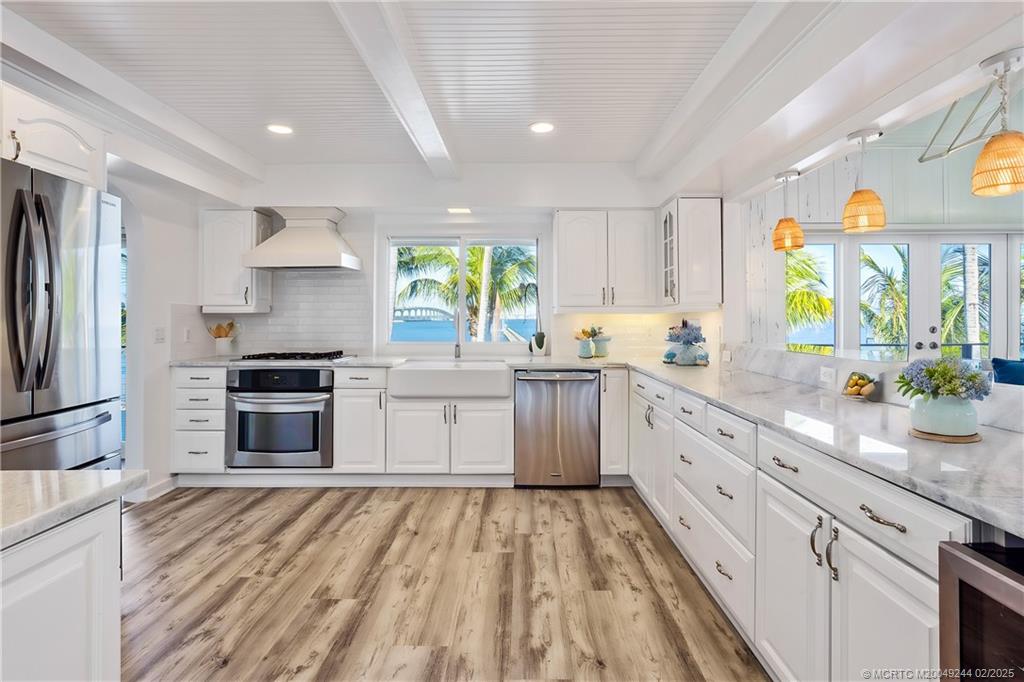 10 South Sewalls Point Road Stuart, FL 34996 - Photo 12 of 79 a kitchen with stainless steel appliances a stove a sink dishwasher a refrigerator white cabinets and wooden floor