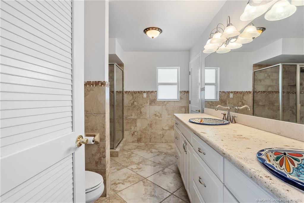 10 South Sewalls Point Road Stuart, FL 34996 - Photo 40 of 79 a bathroom with a granite countertop sink a toilet a mirror and shower