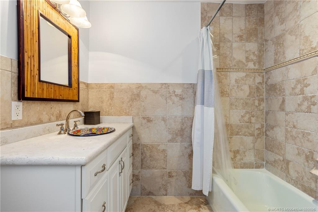 10 South Sewalls Point Road Stuart, FL 34996 - Photo 49 of 79 a bathroom with a granite countertop sink a mirror and a bathtub