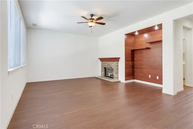 an empty room with wooden floor and a ceiling fan