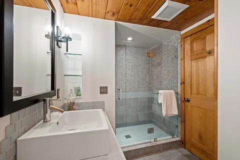 a bathroom with a shower a mirror and a sink