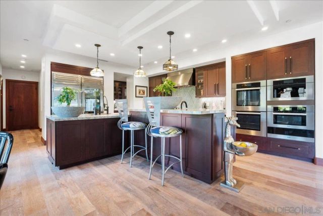 a large kitchen with stainless steel appliances granite countertop a lot of cabinets and wooden floor