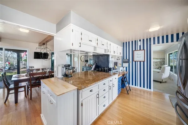 a kitchen with stainless steel appliances granite countertop a refrigerator a stove and a sink with wooden floor
