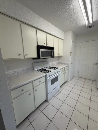a kitchen with white cabinets a sink and a stove