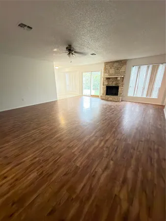 an empty room with wooden floor fireplace and windows