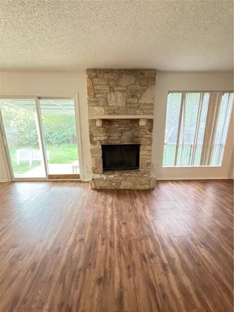 an empty room with wooden floor fireplace and windows
