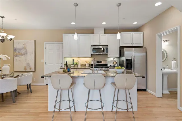 a kitchen with stainless steel appliances a dining table chairs refrigerator and sink