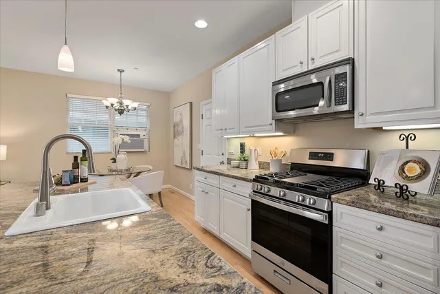 a kitchen with stainless steel appliances granite countertop a stove a sink and a microwave
