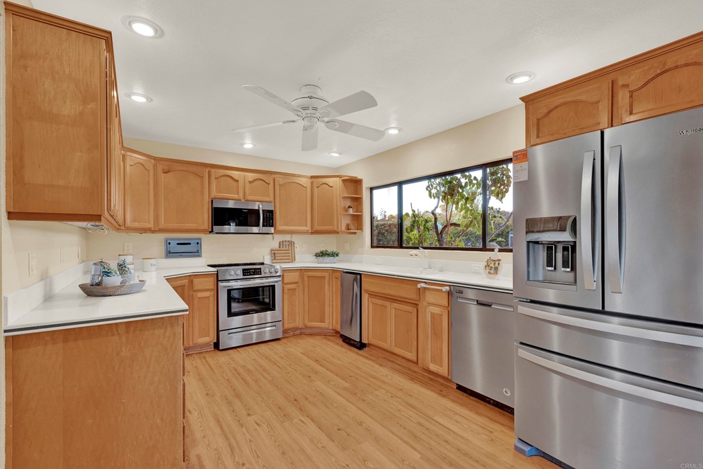 12032 Serena Road Lakeside, CA 92040 - Photo 20 of 55 a kitchen with stainless steel appliances granite countertop a refrigerator a sink dishwasher a stove top oven a refrigerator with white cabinets and wooden floor