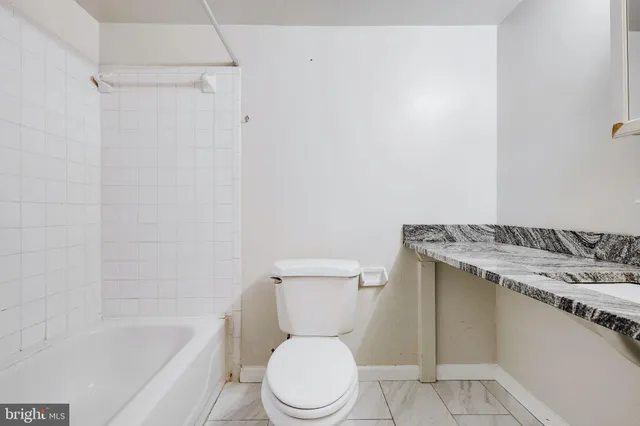 a white toilet sitting next to a bath tub