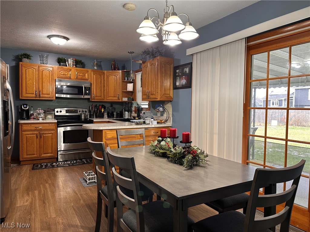 4034 Meister Road Lorain, OH 44053 - Photo 2 of 15 Kitchen with light countertops, stainless steel appliances, brown cabinetry, dark wood finished floors, and pendant lighting