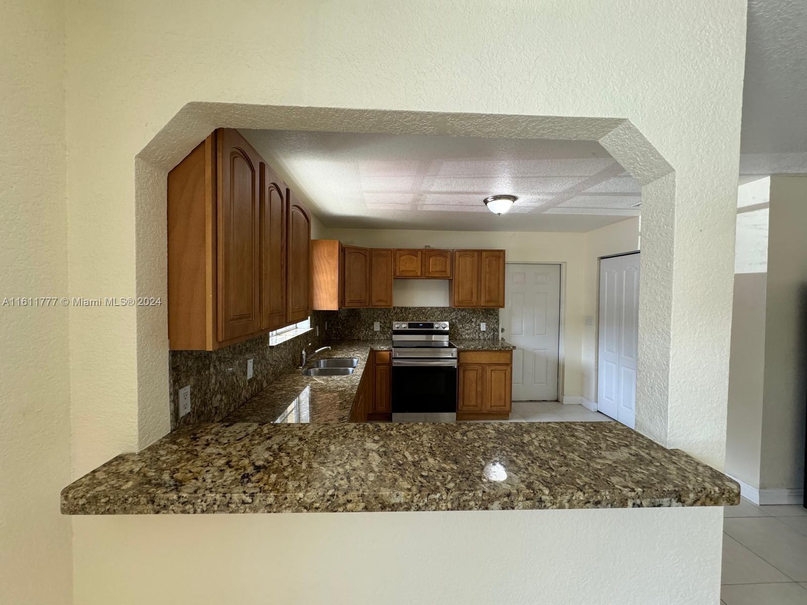 6920 Northwest 4th Avenue, Unit FRONT Miami, FL 33150 - Photo 2 of 13 a kitchen with kitchen island granite countertop a stove a sink and a refrigerator