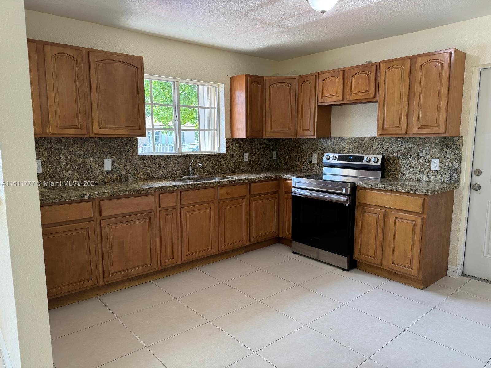 6920 Northwest 4th Avenue, Unit FRONT Miami, FL 33150 - Photo 3 of 13 a kitchen with stainless steel appliances granite countertop a stove sink and cabinets