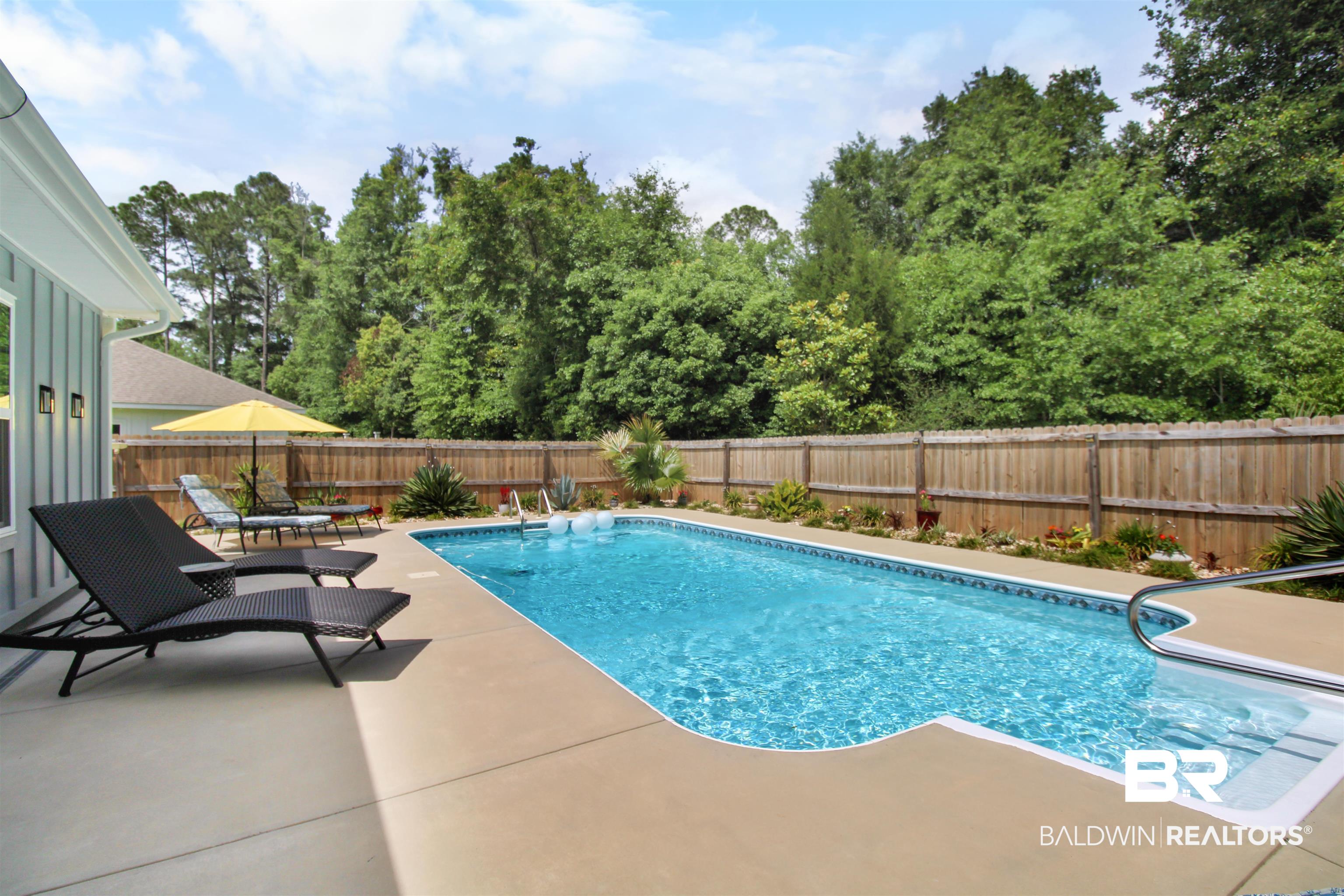 1885 Carly Street Foley, AL 36535 - Photo 30 of 40 Private backyard oasis featuring an in-ground swimming pool with an integrated sun shelf, expansive concrete patio, and a perimeter wooden privacy fence