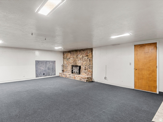 15680 North Beaver Dam Road Collinston, UT 84306 - Photo 31 of 49 Spacious room featuring a stone fireplace, dark grey carpeting, and recessed ceiling lights