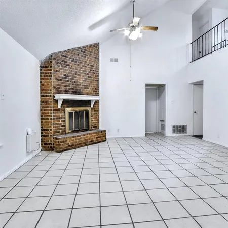 a view of an empty room with a fireplace and a chandelier fan