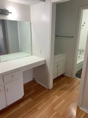 a room with wooden floor and white cabinets