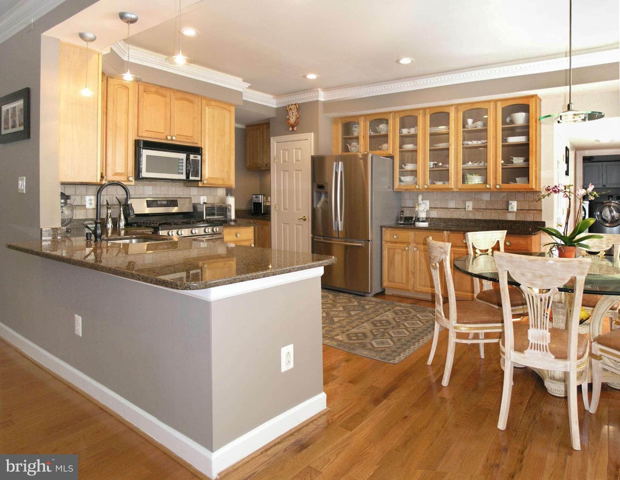 47611 Rhyolite Place Sterling, VA 20165 - Photo 7 of 29 a kitchen with stainless steel appliances granite countertop a stove top oven a refrigerator a dining table and chairs with wooden floor