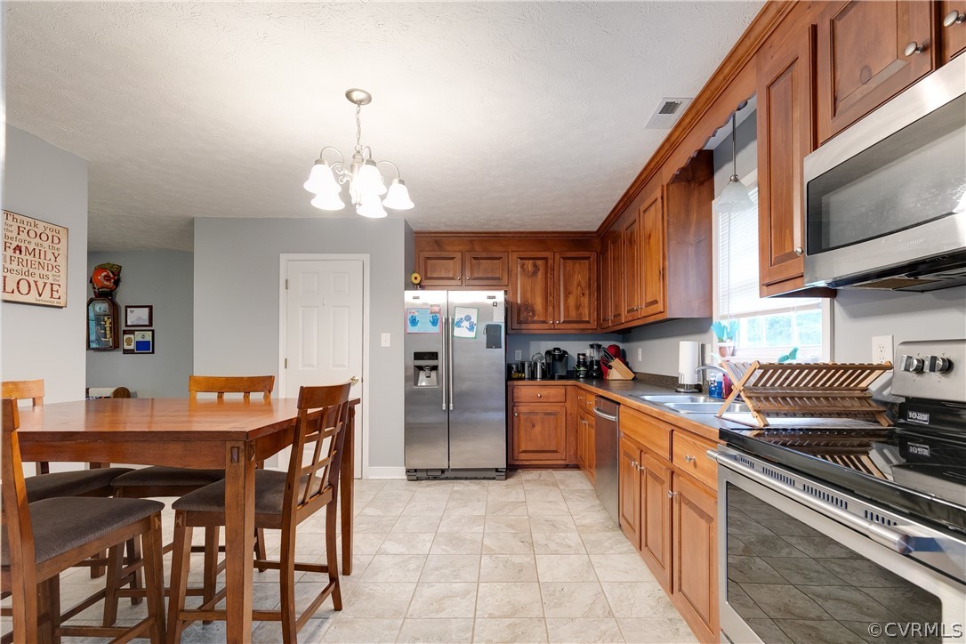 473 Winding Ridge Way Bumpass, VA 23024 - Photo 11 of 25 a kitchen with stainless steel appliances granite countertop a stove top oven a sink a dining table and chairs with wooden floor