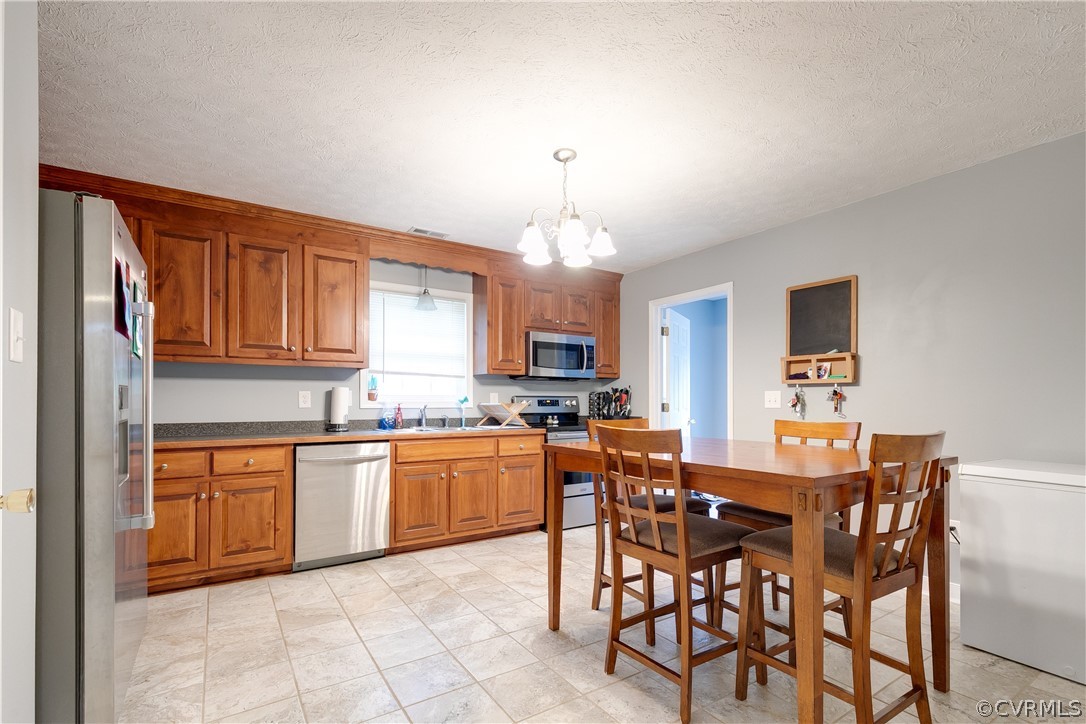 473 Winding Ridge Way Bumpass, VA 23024 - Photo 10 of 25 a kitchen with stainless steel appliances granite countertop a stove top oven a sink a dining table and chairs