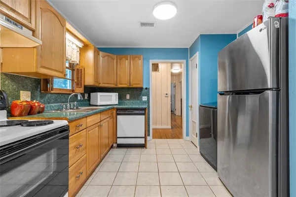 a kitchen with stainless steel appliances granite countertop a refrigerator a stove and a sink
