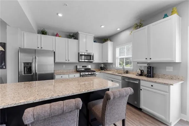 a kitchen with granite countertop white cabinets and stainless steel appliances