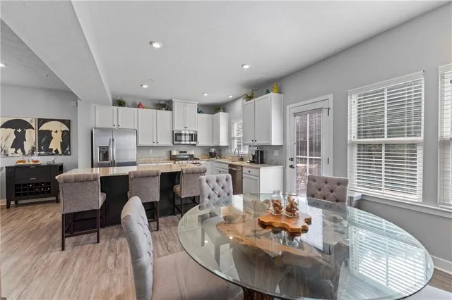 a living room with stainless steel appliances kitchen island granite countertop a dining table chairs and a dining table with wooden floor