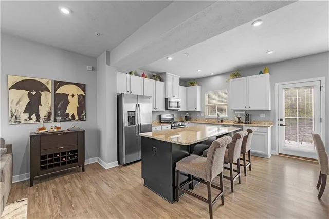a kitchen with refrigerator a stove and a dining table with wooden floor