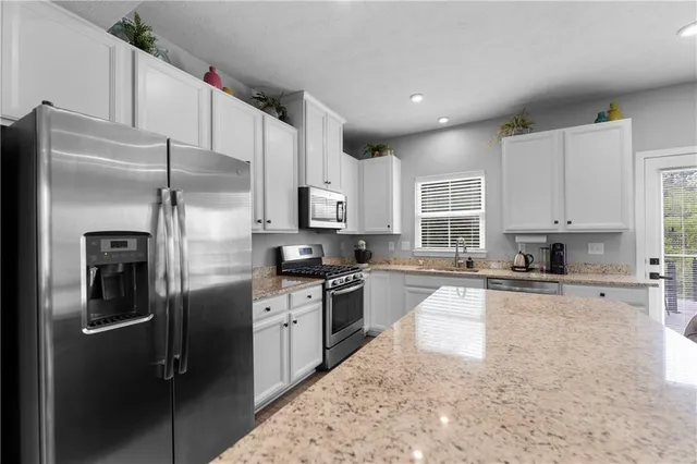 a kitchen with stainless steel appliances granite countertop a refrigerator a stove and a sink