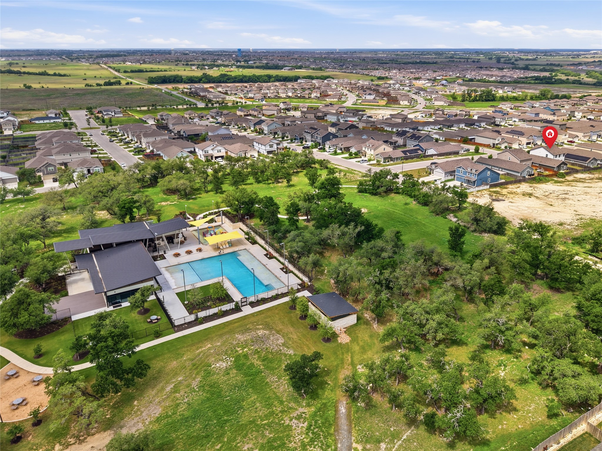 116 Night Riders Way Jarrell, TX 76537 - Photo 38 of 40 Aerial perspective showcasing a community pool area with a modern clubhouse, expansive green spaces, and a surrounding residential development walking distance from subject property
