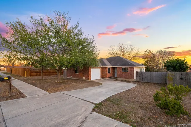 a view of a house with a yard and large trees