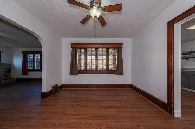 a view of an empty room with window and wooden floor