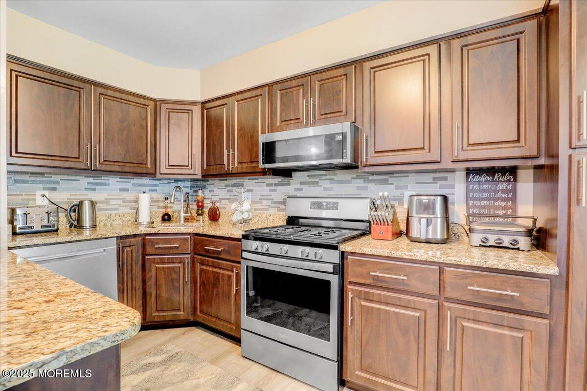 111 Joan Court Jackson, NJ 08527 - Photo 8 of 22 a kitchen with granite countertop a stove top oven a sink dishwasher and cabinets with wooden floor