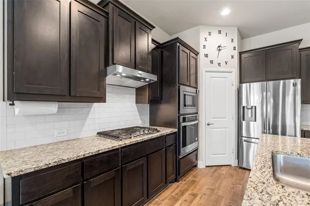 a kitchen with stainless steel appliances granite countertop a refrigerator and a stove