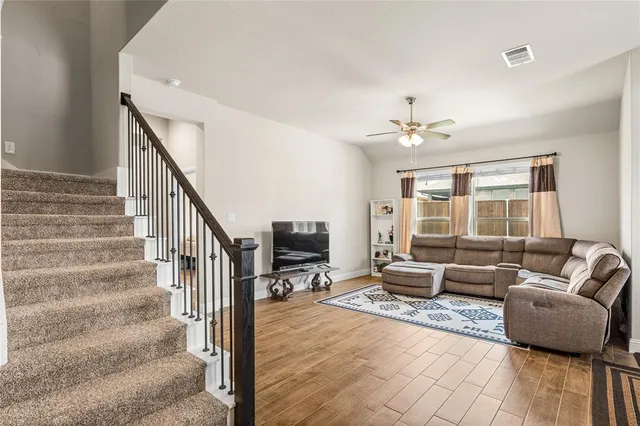 a living room with furniture windows and a ceiling fan