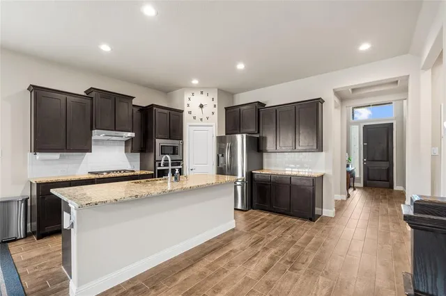 a large kitchen with stainless steel appliances kitchen island granite countertop a refrigerator stove and oven