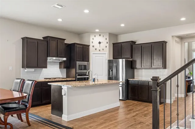 a kitchen with stainless steel appliances kitchen island granite countertop a refrigerator and a stove top oven